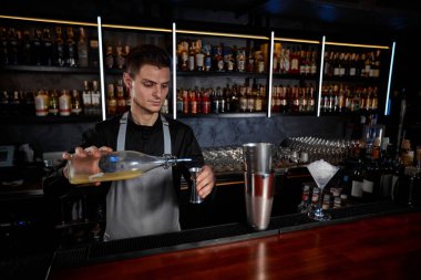 Önlüklü barmen karıştırıcıya malzeme ekliyor.