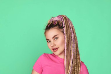 Rastalı kadın yeşil arka planda gülümsüyor.