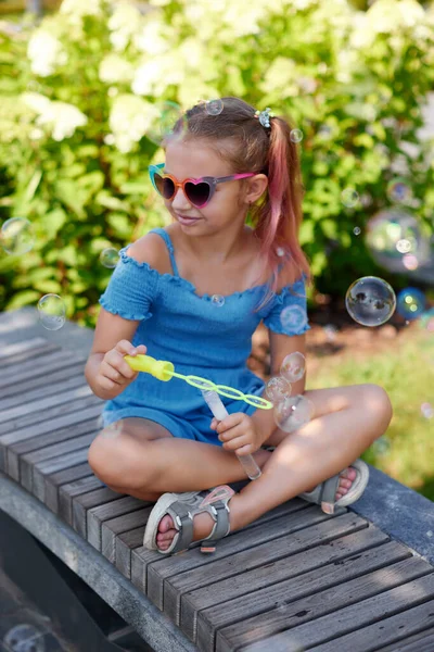 Gyermek lány fúj szappan buborékok a parkban. — Stock Fotó