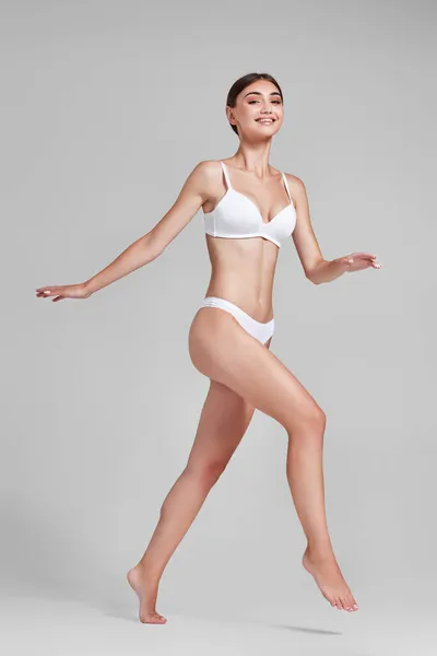 Жінка з ідеальним тілом у білій білизні стрибає — стокове фото