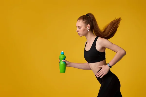 Μια νεαρή γυναίκα τρέχει και κρατάει ένα μπουκάλι νερό. — Φωτογραφία Αρχείου