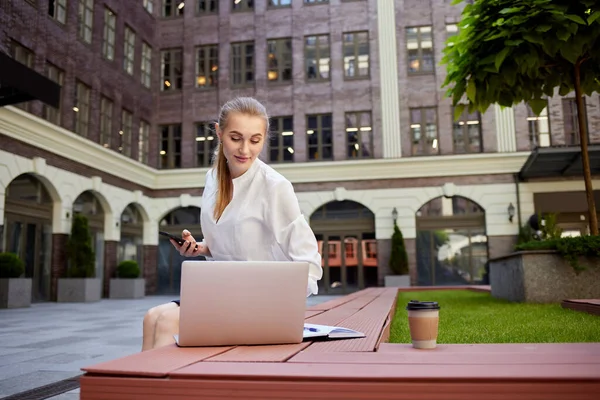 Geschäftsfrau mit Smartphone am Laptop — Stockfoto