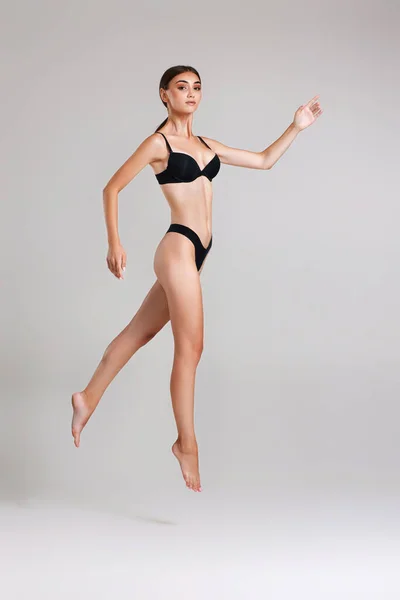 Красива жінка з ідеальним тілом в чорній білизні стрибає — стокове фото