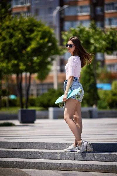 Skridskoåkare kvinna i solglasögon med blå skateboard utomhus — Stockfoto