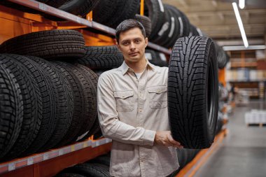 Erkek müşteri süpermarkette yeni lastikler alıyor..