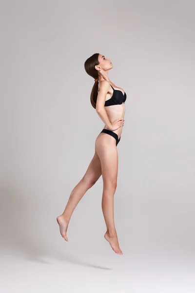 Piękna kobieta z doskonałym ciałem w czarnej bieliźnie skoki — Zdjęcie stockowe