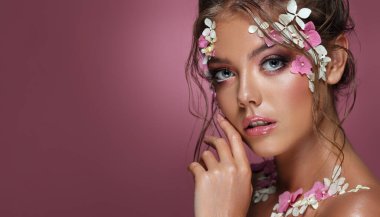 Pembe arka planda çiçekleri olan güzel beyaz kadın..