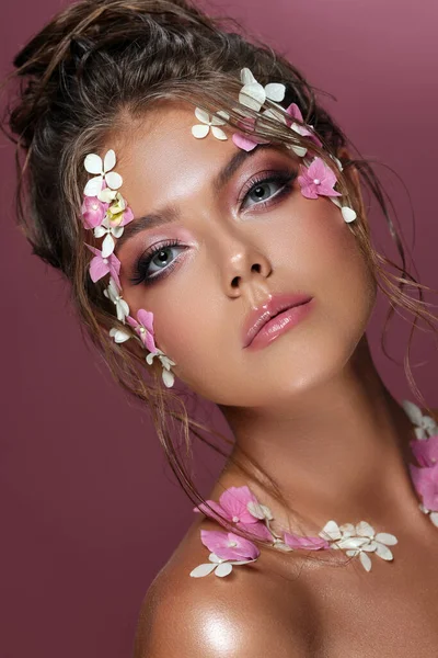 Frumoasa femeie caucaziană cu flori pe fundal roz. — Fotografie, imagine de stoc