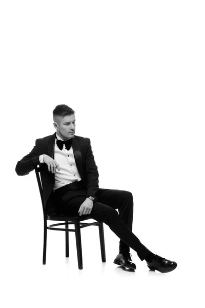 Hombre guapo en esmoquin sentado en la silla — Foto de Stock