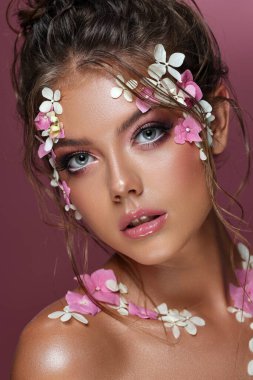Pembe arka planda çiçekleri olan güzel beyaz kadın..
