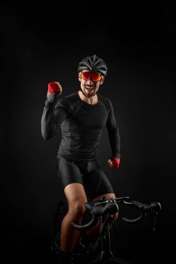 Erkek bisikletçi siyah arka planda bisiklet sürüyor.