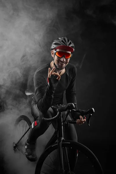 Ciclista di sesso maschile con bicicletta da strada su sfondo nero — Foto Stock