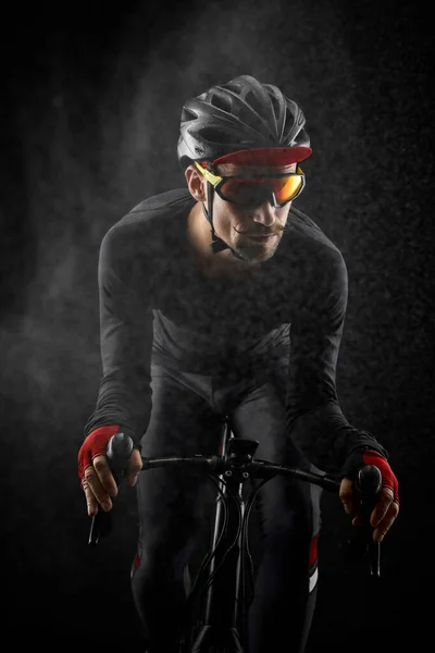 Männlicher Radfahrer auf Rennrad auf schwarzem Hintergrund — Stockfoto