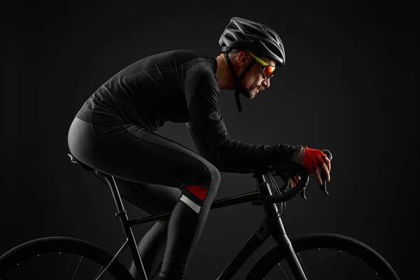 Männlicher Radfahrer auf Rennrad auf schwarzem Hintergrund — Stockfoto