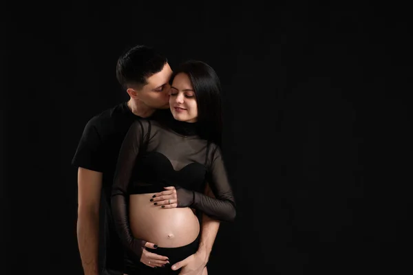 Pareja esperando bebé y abrazándose en negro fondo — Foto de Stock