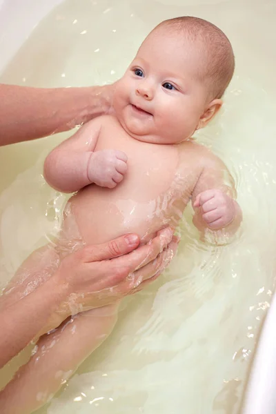 Mutter badet ihr Baby in einer weißen kleinen Plastikwanne — Stockfoto