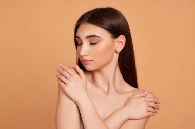 Kadın omzuna dokunuyor ve kusursuz yumuşak teninin tadını çıkarıyor.