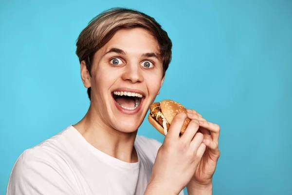 Molto affamato giovane che tiene gustoso hamburger — Foto Stock