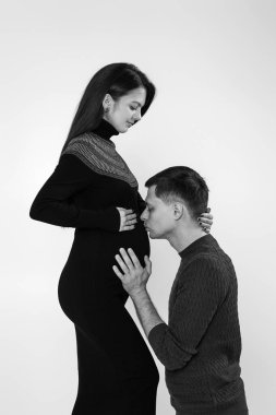 Genç ve güzel hamile karısının karnını dinleyen bir adam.