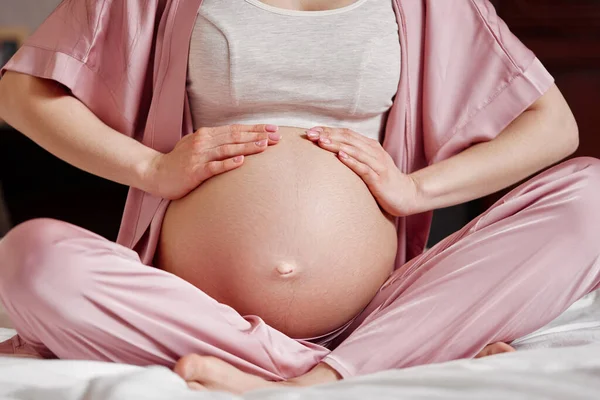 Těhotná žena drží ruce na břiše — Stock fotografie
