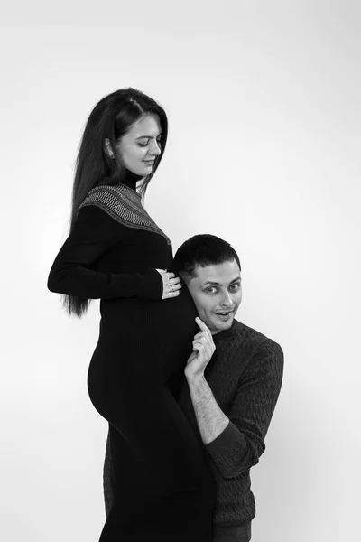 Hombre escuchando a su joven hermosa embarazada esposas vientre — Foto de Stock