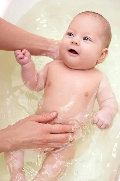 Mother bathes her baby in a white small plastic tub — Stock Photo, Image
