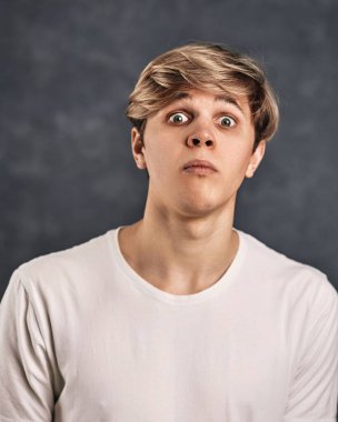 Koyu gri arka planda suratını buruşturan yakışıklı adam.