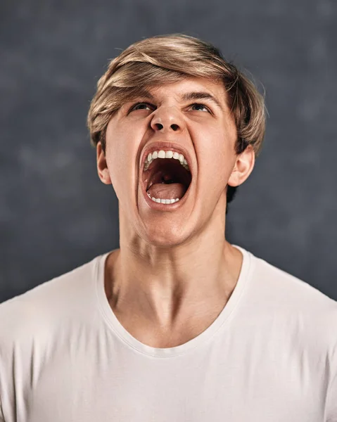 Furious, enraged young man over gray background — Fotografia de Stock