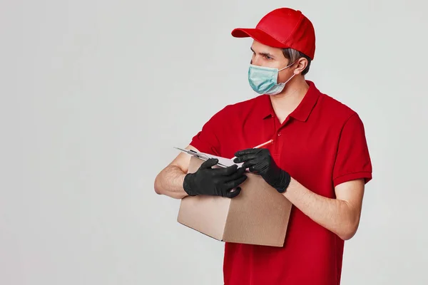 赤いキャップフェイスマスク、空の段ボール箱の配達人の従業員 — ストック写真