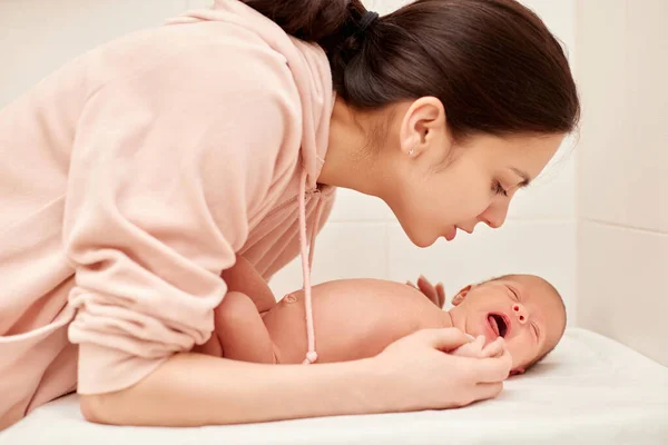 Young mother kissing her cute newborn baby — Stock Photo, Image