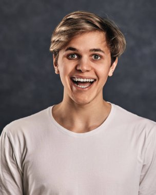 Gri arka plandaki komik, genç yakışıklı adam..