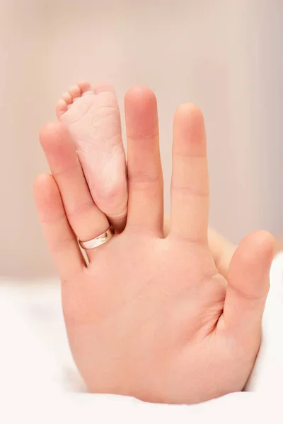 Mains du père tenant les pieds du nouveau-né. — Photo