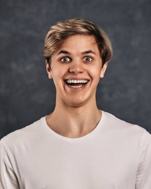 Gri arka plandaki komik, genç yakışıklı adam..