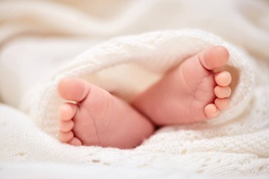 tiny newborn baby feet on white blanket