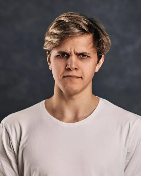 Young man frowning on gray background. Human emotions — Foto Stock