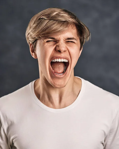 Furious, enraged young man over gray background — Fotografia de Stock