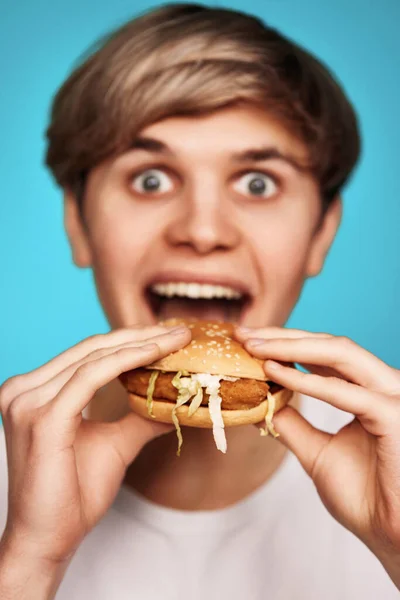 Joven muy hambriento sosteniendo sabrosa hamburguesa — Foto de Stock