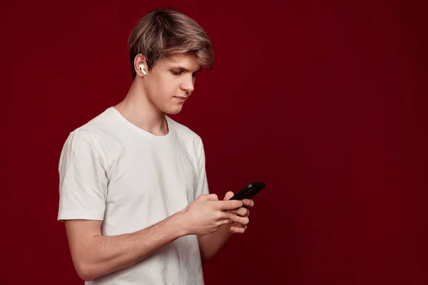 Man with earphones listens music while looking at content on phone screen — Fotografia de Stock