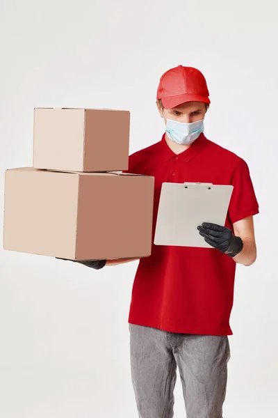 Delivery man employee in red cap face mask, empty cardboard box