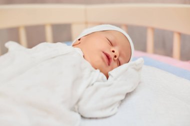 Sevimli yeni doğmuş bebek yatakta uyuyor.