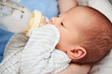 Annesi küçük tatlı kızını süt şişesiyle besliyor.