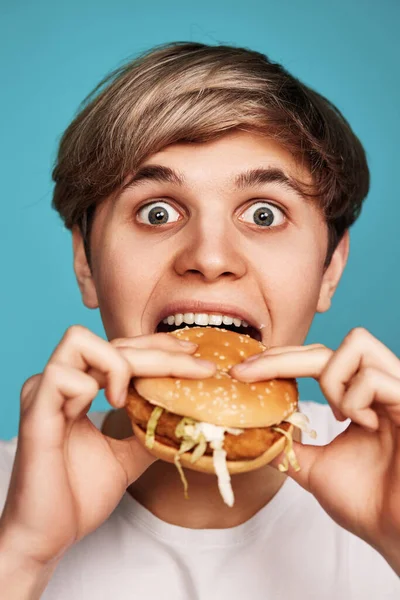 Дуже голодний молодий чоловік тримає смачний гамбургер — стокове фото