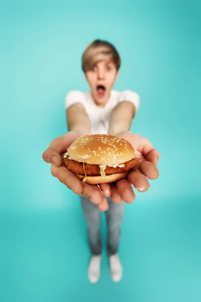 Дуже голодний молодий чоловік тримає смачний гамбургер — стокове фото
