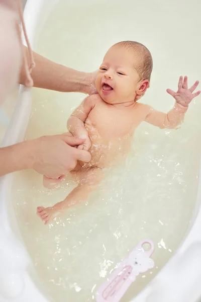 Mother bathes her baby in a white small plastic tub — Stock Photo, Image