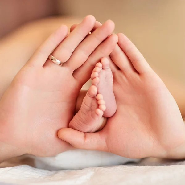 Bebeğin yeni doğmuş ayaklarını tutan babanın elleri. — Stok fotoğraf