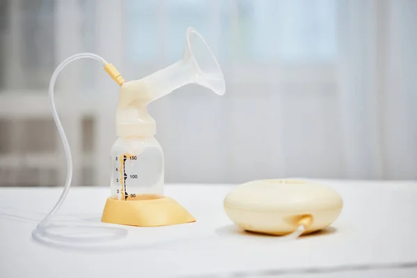 Breast pump with empty baby bottle on table — Stockfoto