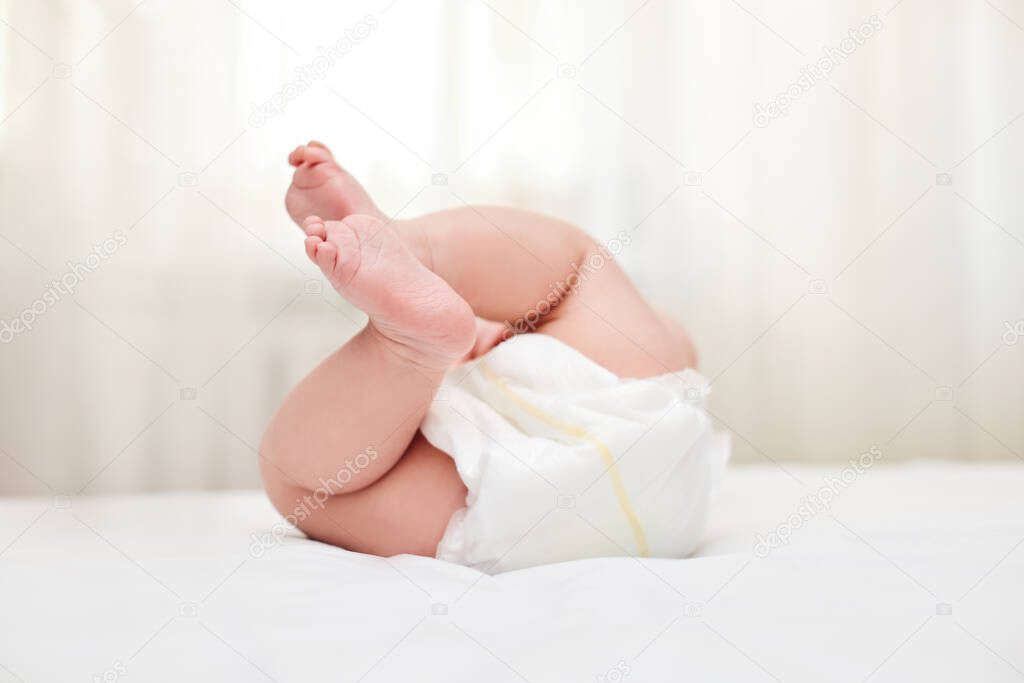 Cute little baby in diaper on bed. focus on legs