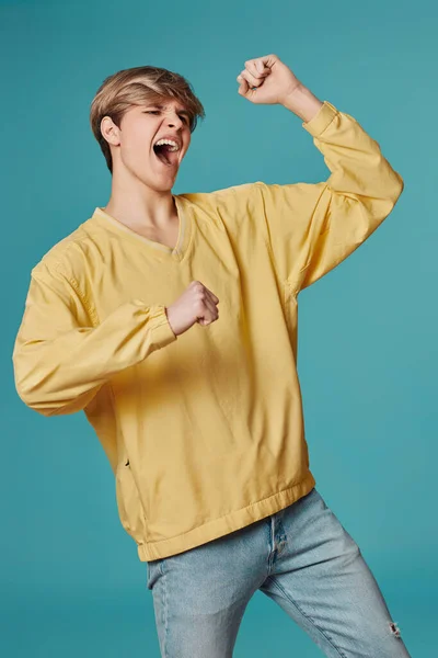 Excited Young Man Casual Yellow Clothes Dancing Isolated Pastel Blue — Stock fotografie