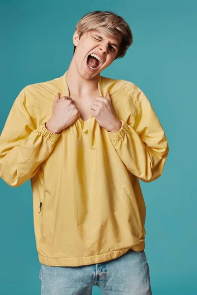 Сумасшедший Молодой Человек Непринужденной Желтой Одежде Танцует Изолированно Голубом Фоне — стоковое фото