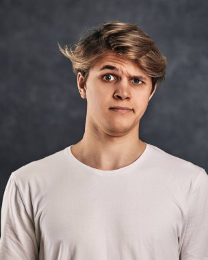 Yüzünde gri arka planda tişörtü olan genç yakışıklı bir adam..